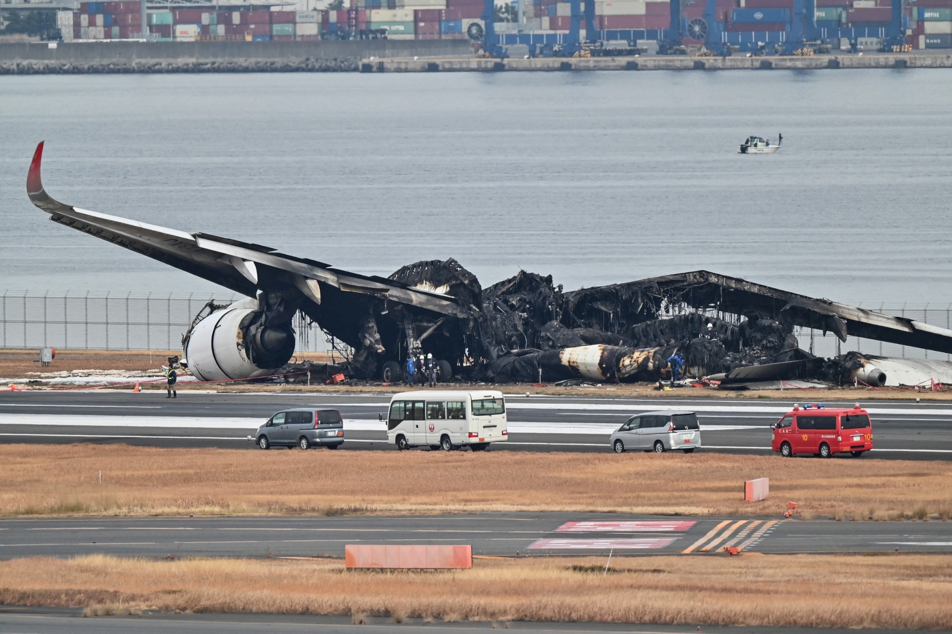 PHOTO: Officials look at the burning wreckage of a Japan Airlines passenger plane on the runway of Tokyo International Airport in Haneda, Tokyo, on January 3, 2024.