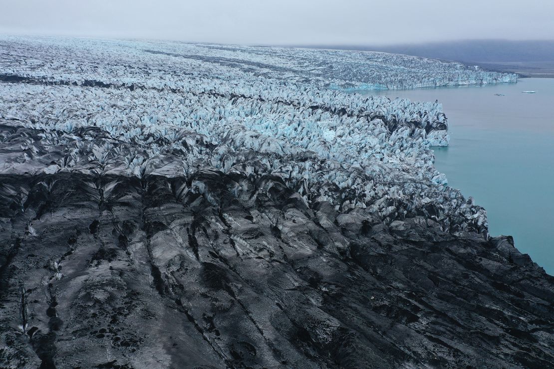 The retreating Bredaamkurjokull glacier, part of which has been blackened by volcanic ash and rocks, ends at the Jokulsarlon lagoon on August 15, 2021 near Hof, Iceland.