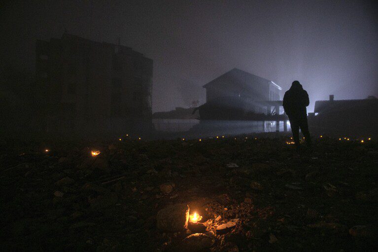 People hold a minute of silence on the ruins of destroyed buildings, marking one year since the earthquake, in the city of Antakya, southern Turkey, Tuesday, February 6, 2024. Millions of people across Turkey on Tuesday mourned the loss of more than 53,000 friends, loved ones and neighbors in the catastrophic earthquake that... It hit the country a year ago.  To mark what he calls "disaster of the century," The government arranged a series of events to commemorate the first anniversary of the disaster in southern Turkey.  (AP Photo/Metin Yuksu)