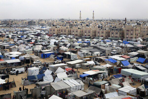 FILE - A tent camp shelters Palestinians displaced by the Israeli attack in Rafah, Gaza Strip, on February 27, 2024. The tent camps stretch more than 16 kilometers (10 miles) along the Gaza coast, filling the beach and extending into empty lots, fields and city streets.  (AP Photo/Hatem Ali, File)