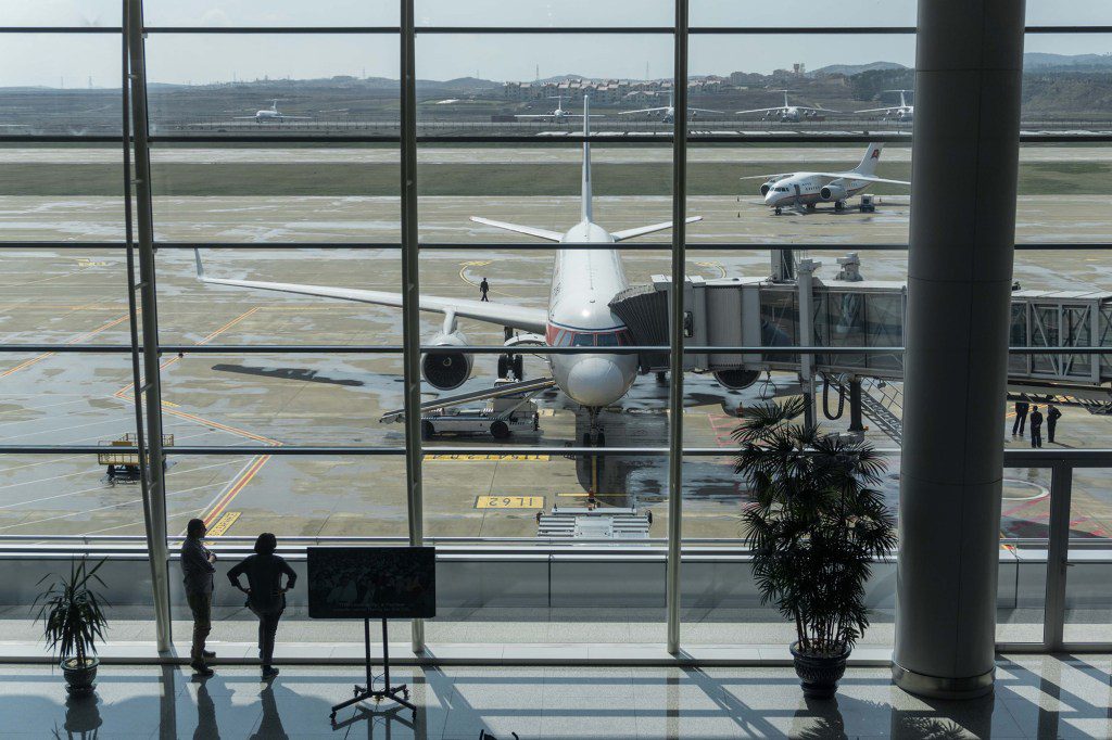 Passengers stand in front of an Air Koryo plane at Pyongyang airport on April 17, 2017.